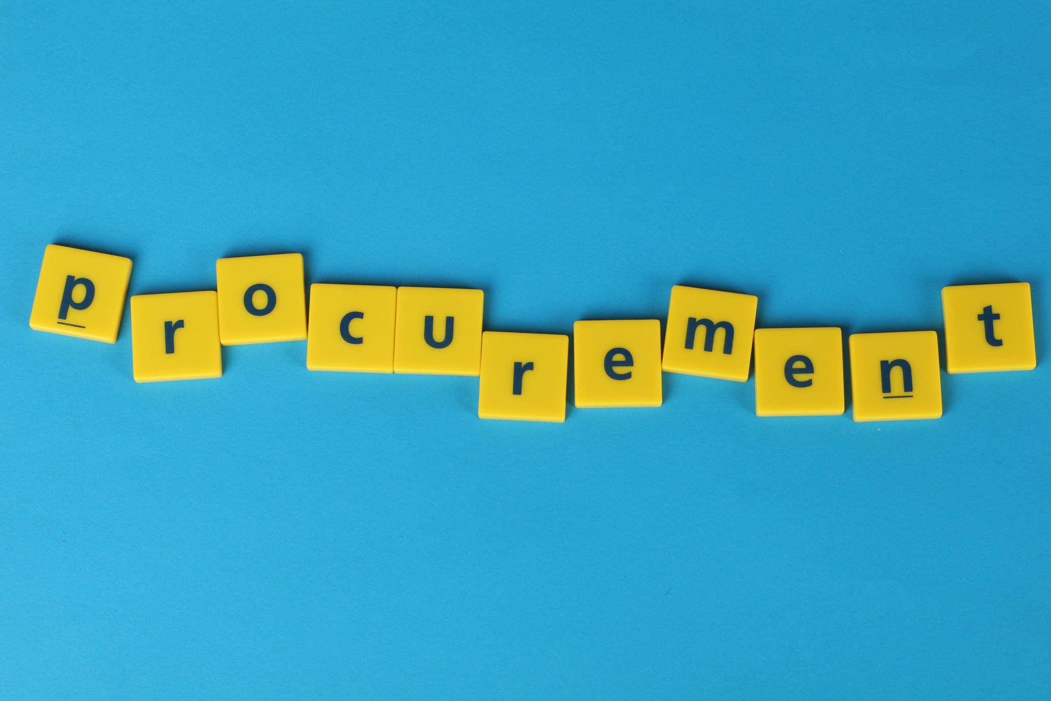 A picture of yellow tiles spelling out the word procurement